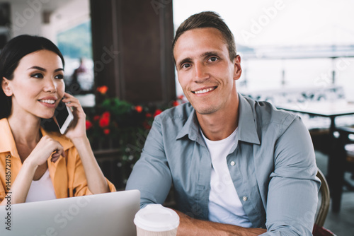 Obraz na płótnie Cheerful diverse man and woman sitting in cafe with gadgets w salonie
