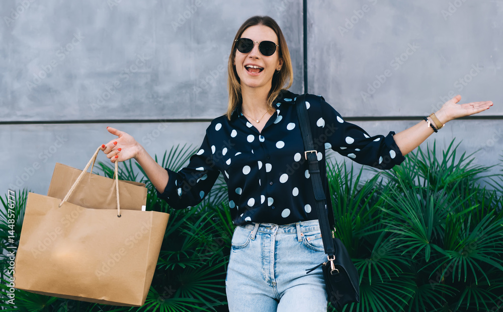 Cheerful woman showing purchases in paper bags on street