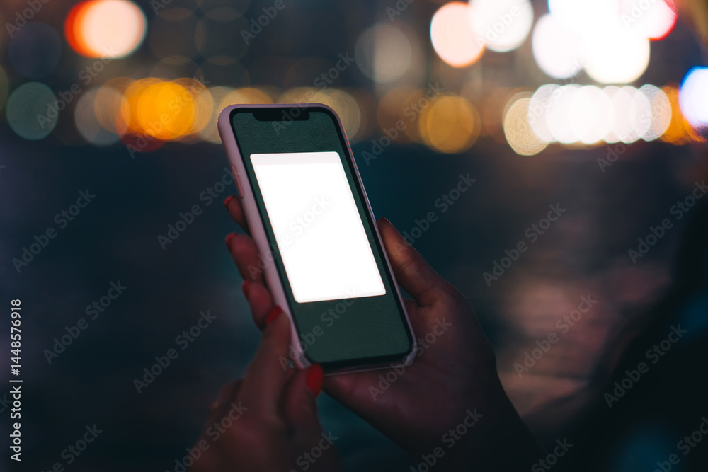 Unrecognizable woman watching at copy space screen of smartphone on blurred night city background