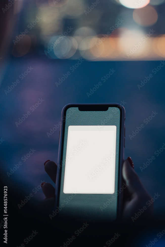 Smartphone with copy space screen in hand of unrecognizable woman on blurred background of night river and city
