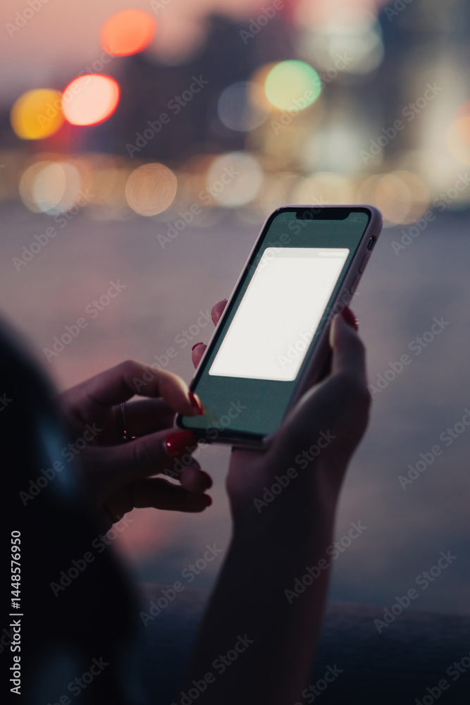Crop young woman using smartphone with copy space screen on background of blurred night city