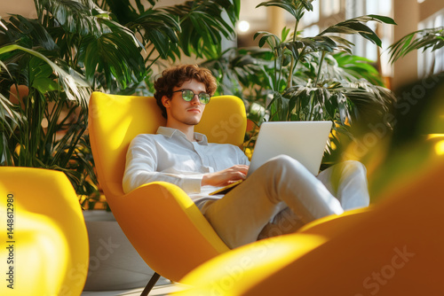 Relaxed Young Entrepreneur Working on Laptop in Modern Green Workspace