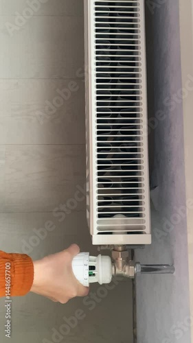A woman's hand sets the temperature on the radiator