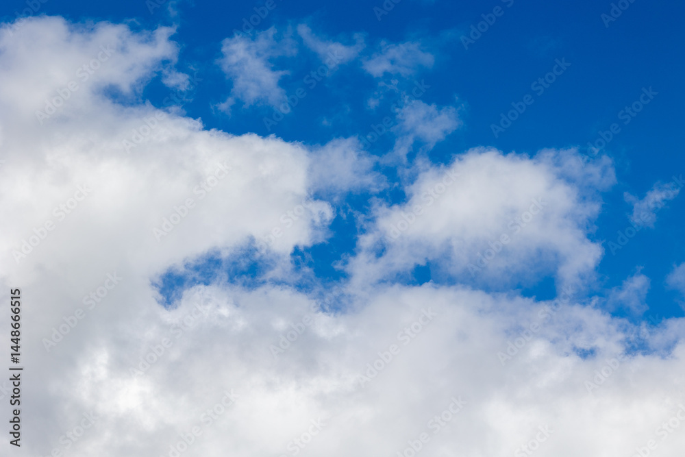 Fototapeta premium White clouds drifting across vibrant blue sky