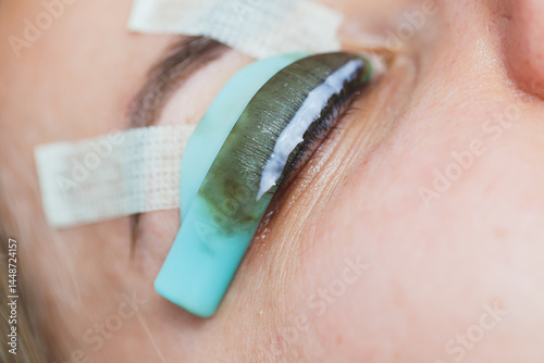 Obraz na płótnie Eyelash lamination procedure on a woman's face. A cosmetologist glues long eyelashes with tweezers onto a woman's eye during an eyelash extension procedure. w salonie