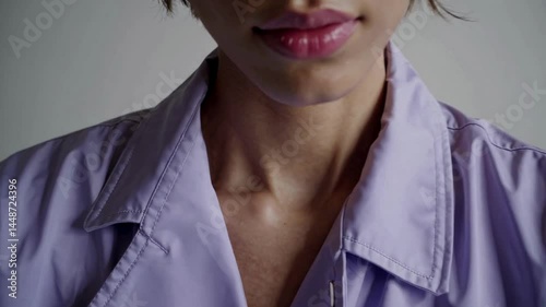 Young woman in lavender blouse with serious expression close-up