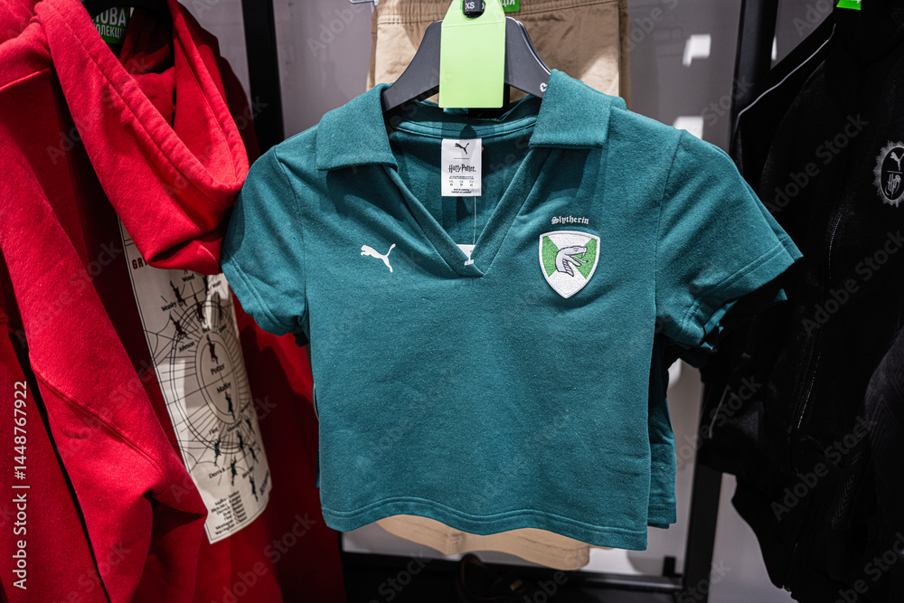 Naklejka premium Green Slytherin themed cropped Puma shirt displayed on clothing rack among other apparel items