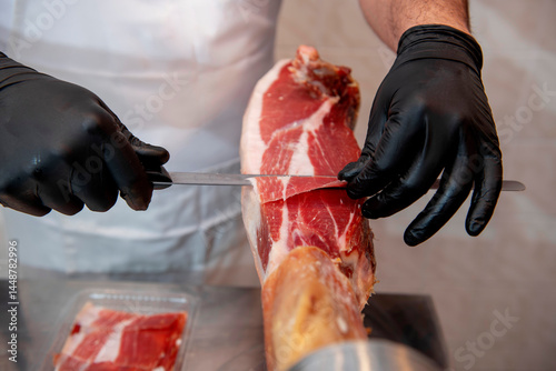 Butcher slicing serrano ham in a butcher shop