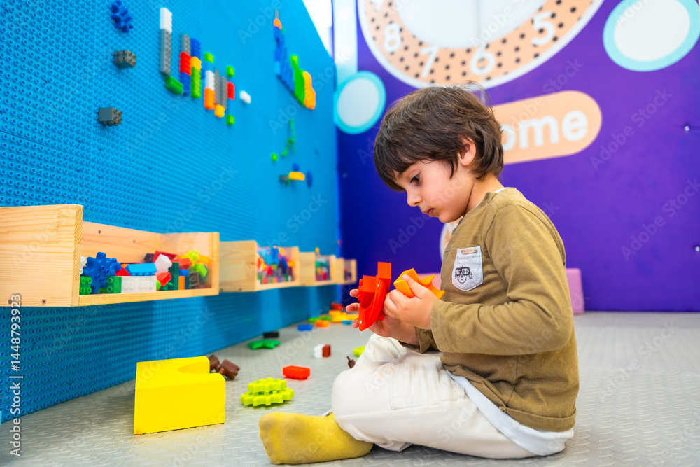 Child playing with colorful interlocking plastic bricks in playroom