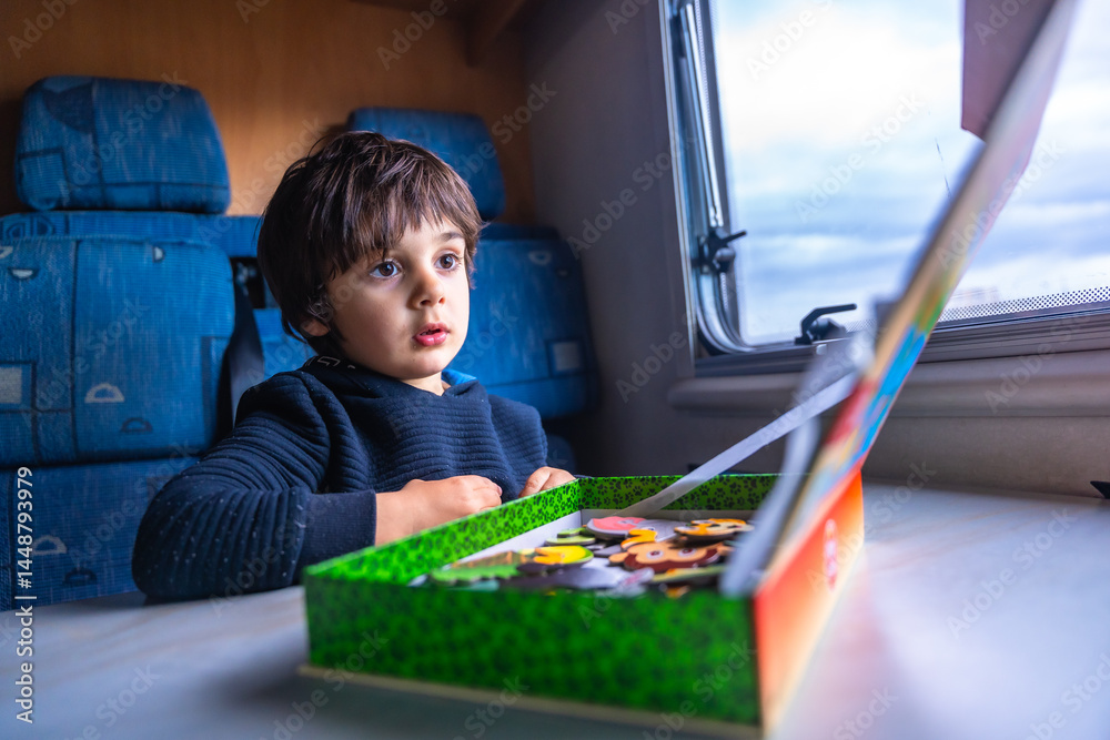 Child playing with puzzle inside camper van at fangar beach, ebro delta
