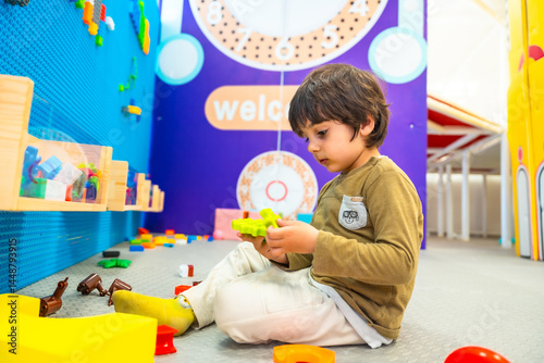 Cute boy playing with building blocks in playroom