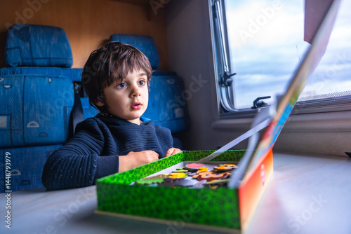 Child playing with puzzle inside camper van at fangar beach, ebro delta