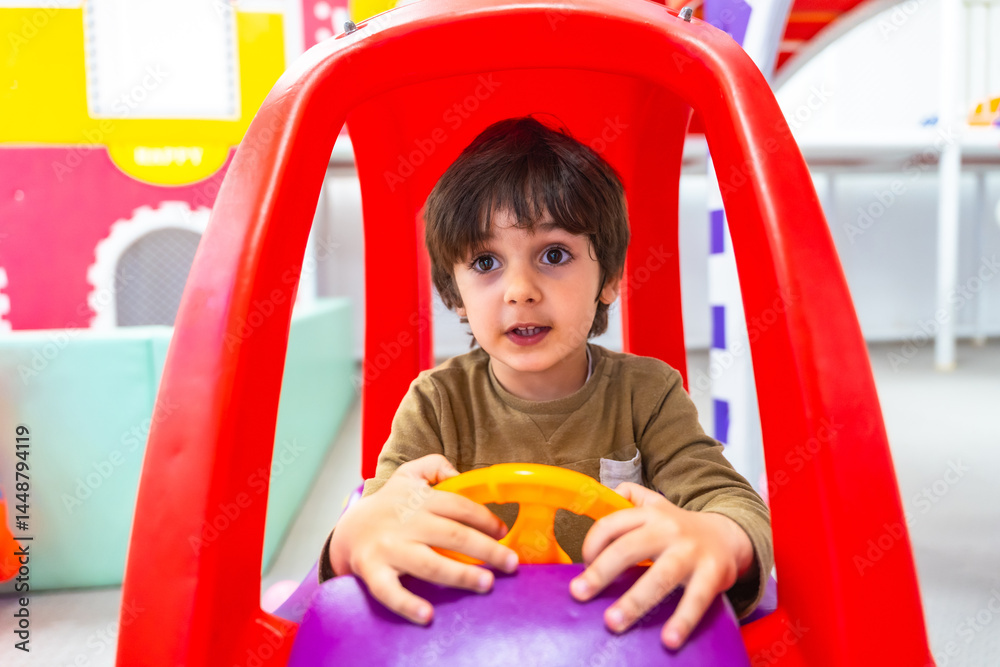 Child playing with toy car steering wheel in kindergarten, imaginary driving fun