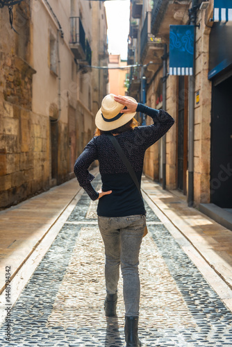 Obraz na płótnie Tourist walking in medieval city of tarragona, spain, holding her hat w salonie