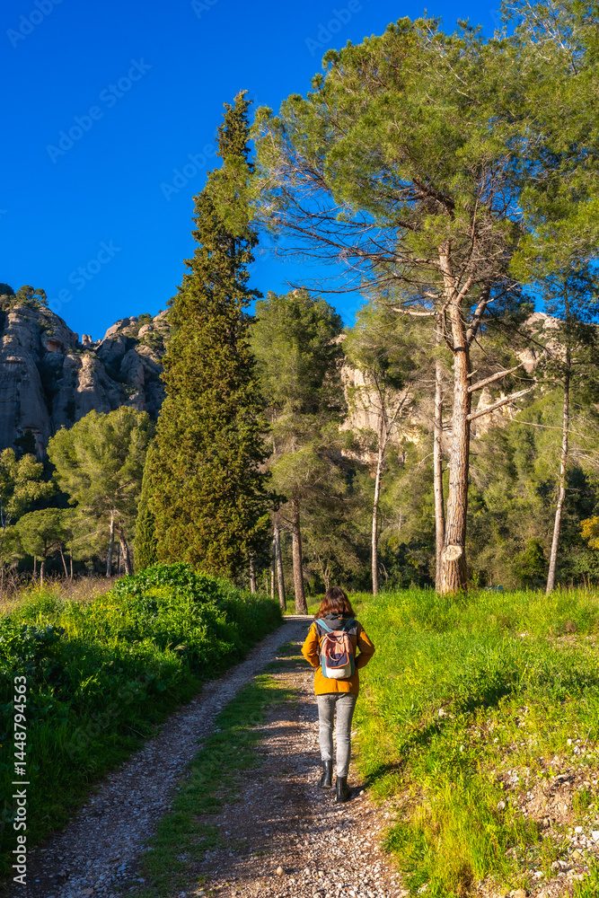 Tourist walking on a path near montserrat mountains on a sunny day