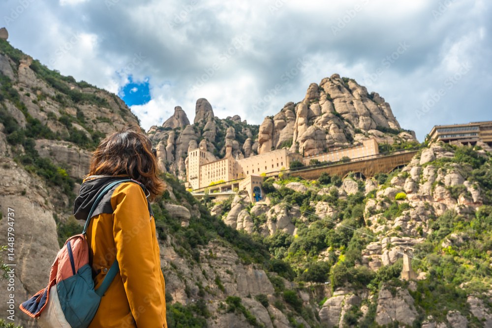 Tourist enjoying the view of santa maria de montserrat abbey in the montserrat mountains, catalonia, spain
