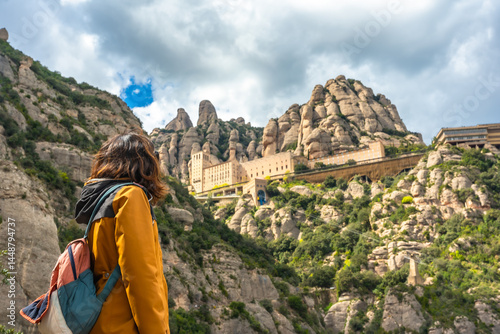 Tourist enjoying the view of santa maria de montserrat abbey in the montserrat mountains, catalonia, spain