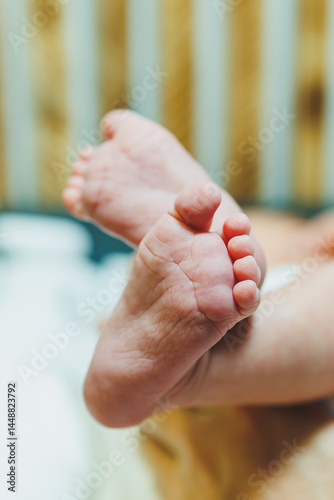 Obraz na płótnie Close-up of baby feet in parent's hands. Baby feet with little toes. Cute photo of baby feet. w salonie