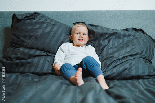 Obraz na płótnie Funny 2 year old little boy wearing pajamas resting and playing in bed. Little toddler boy playing in bed. w salonie