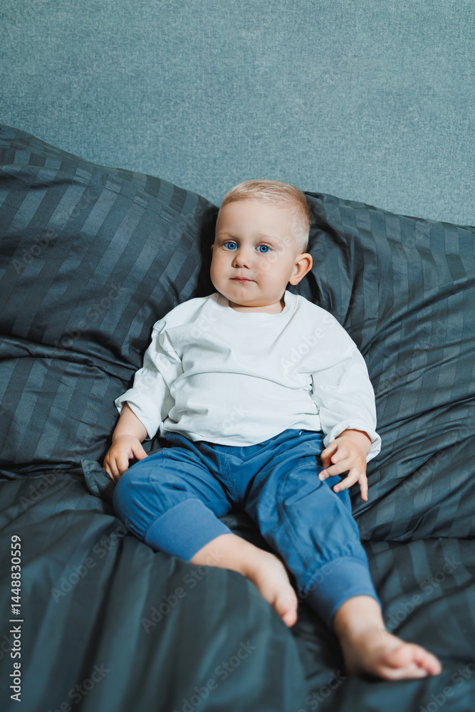 Funny 2 year old little boy wearing pajamas resting and playing in bed. Little toddler boy playing in bed.