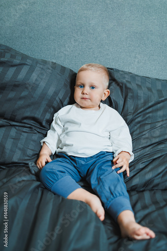 Obraz na płótnie Funny 2 year old little boy wearing pajamas resting and playing in bed. Little toddler boy playing in bed. w salonie