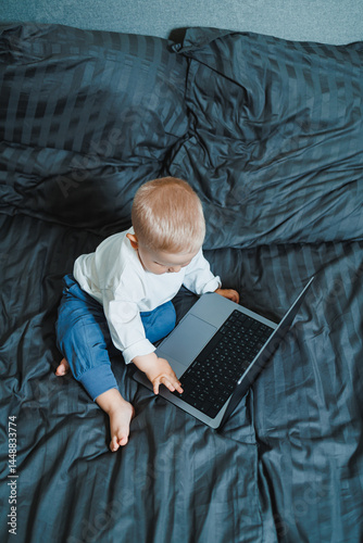 Obraz na płótnie Cute little boy 2 years old sitting at home using laptop. Toddler boy watching video on laptop. Modern digitalization of children. Child watching educational videos on laptop. w salonie