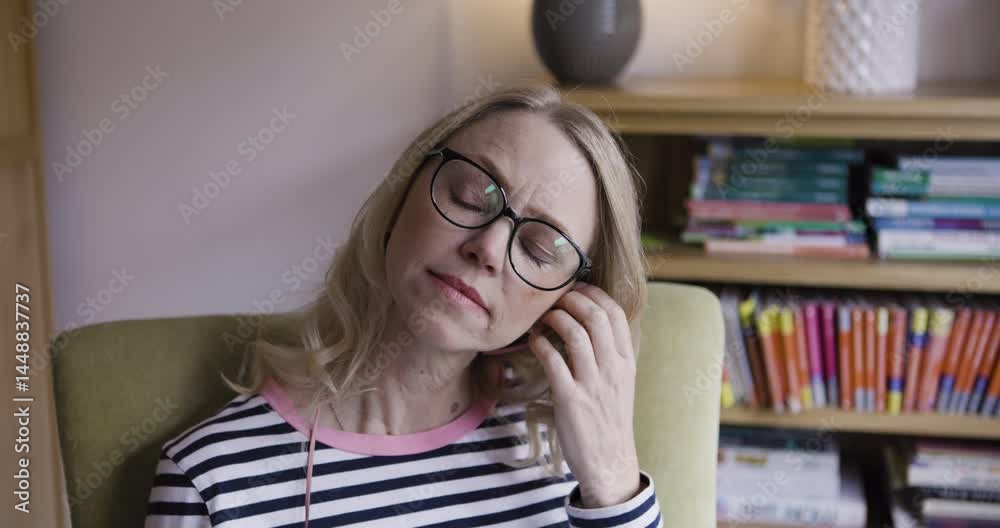 Music, relax and woman with a phone in a chair for a calm podcast in the living room of her house. Radio, audio and mature content person streaming and listening to sound from mobile and earphones