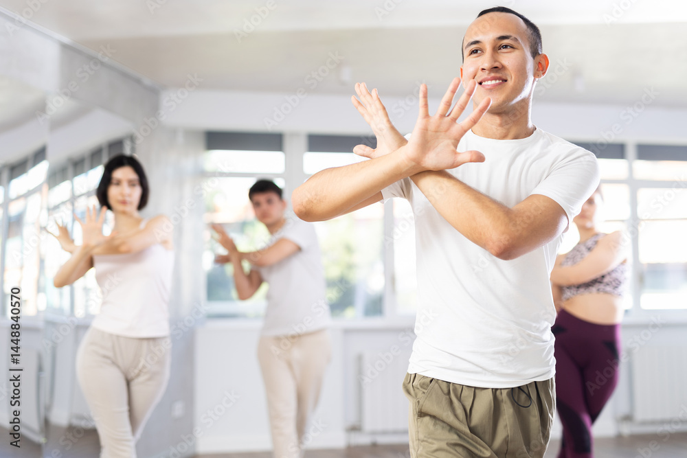 Portrait of active young man enjoying modern energetic dancing in group at street dance studio