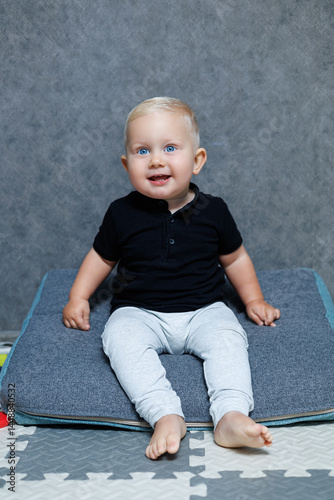 Obraz na płótnie Blue-eyed blond boy 2 years old playing at home in the room. Toddler boy smiling looking at the camera. Home clothes for children. w salonie