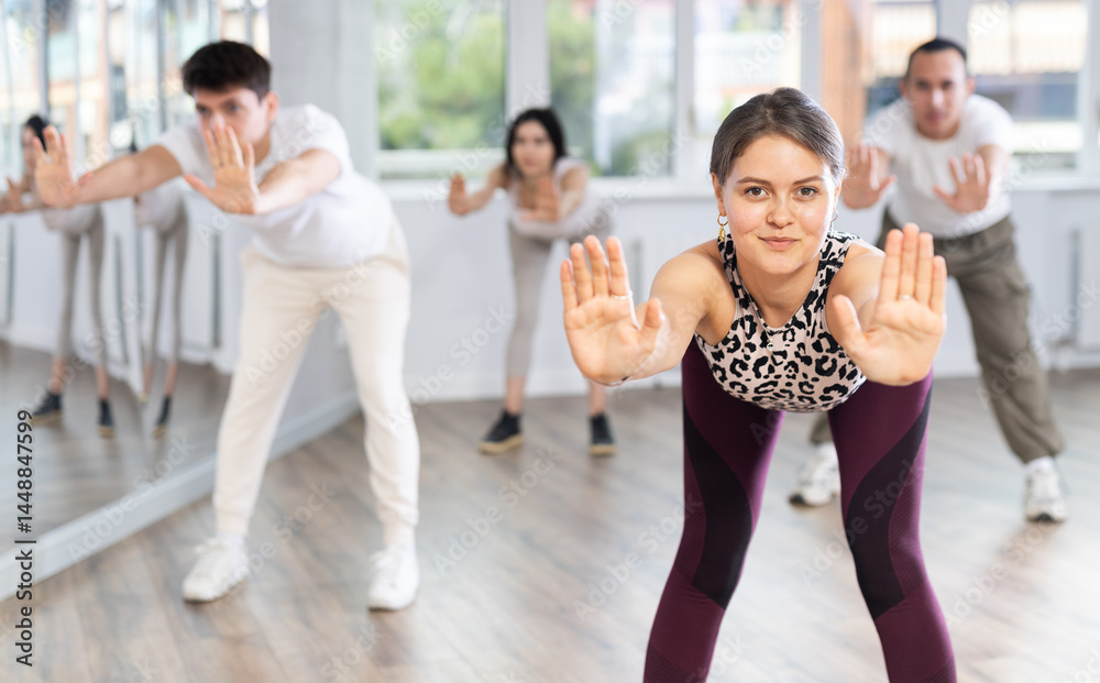 Obraz premium Group of young men and women doing warm up before dance class in studio