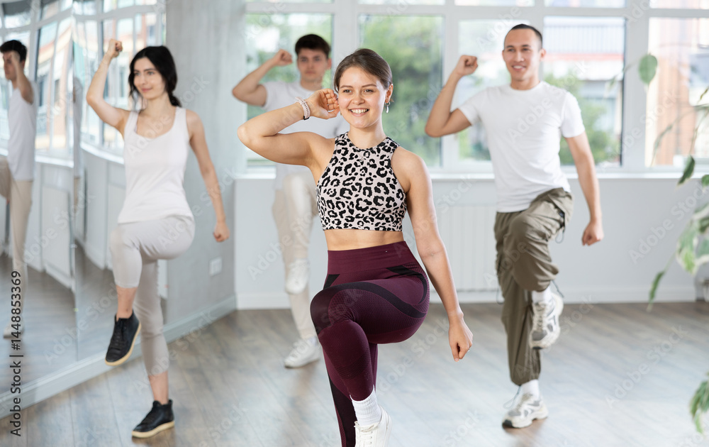 Fototapeta premium Smiling active young girl enjoying contemporary vigorous dance at group class in light mirrored studio