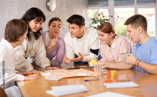 Group of positive younger people playing tabletop game