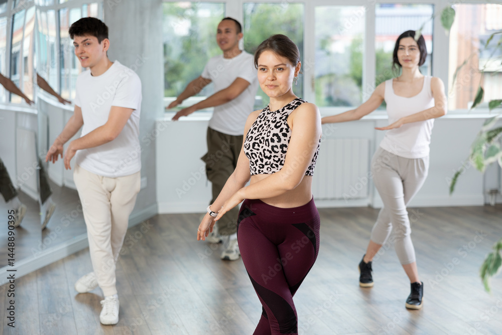 Obraz premium Group of young men and women rehearsing jazz funk dance in studio
