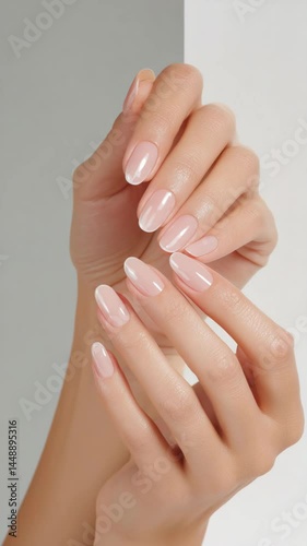 Elegant woman's hands displaying a French manicure with nude polish on oval shaped nails, promoting beauty and nail care