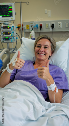 A middle aged Caucasian woman smiles and shows two thumbs up while lying in hospital bed. Vertical photo of smiling woman during recovery in hospital room. Patient satisfaction