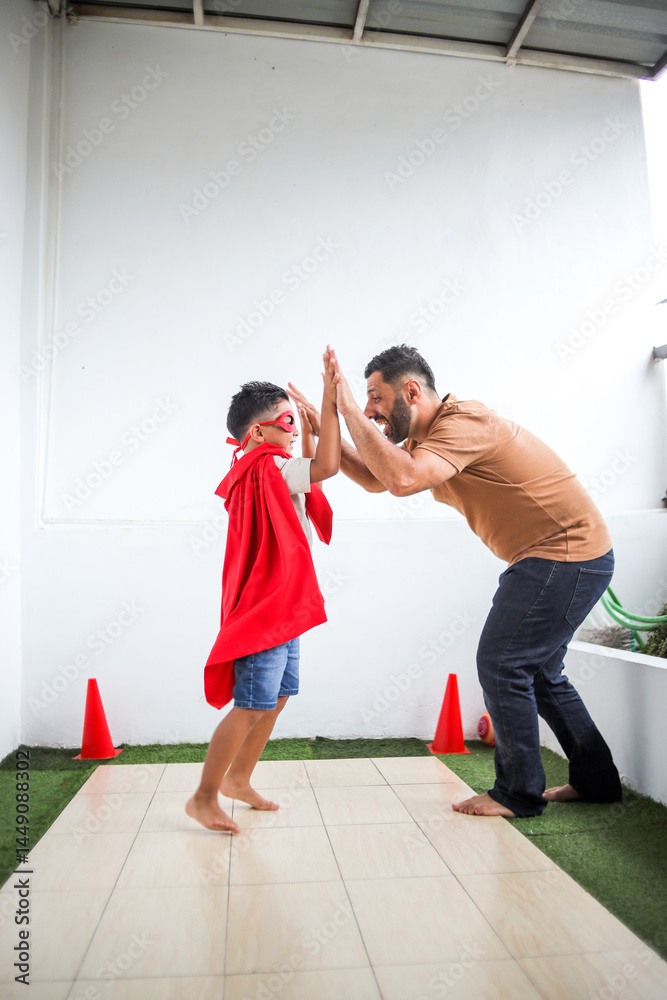 Fototapeta premium Father And His Son Wearing Superhero Costumes Doing High Five