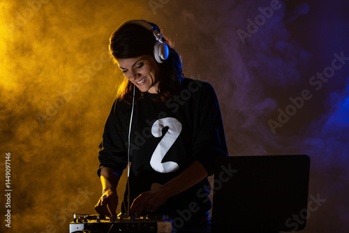 Female DJ on a mixer. Girl playing texhno music against smoke background.