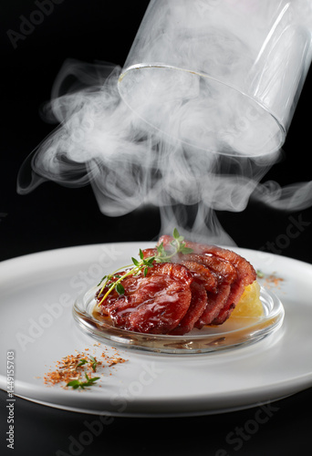 Closeup of fried duck breast on a plate decorated with dry ice
