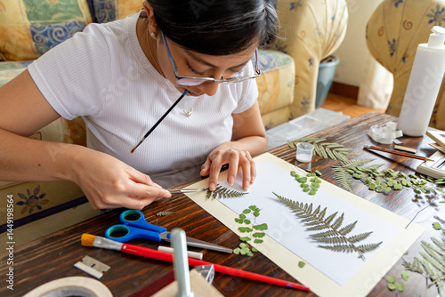Artistic woman using her tools to glue dry branches to a sheet photo