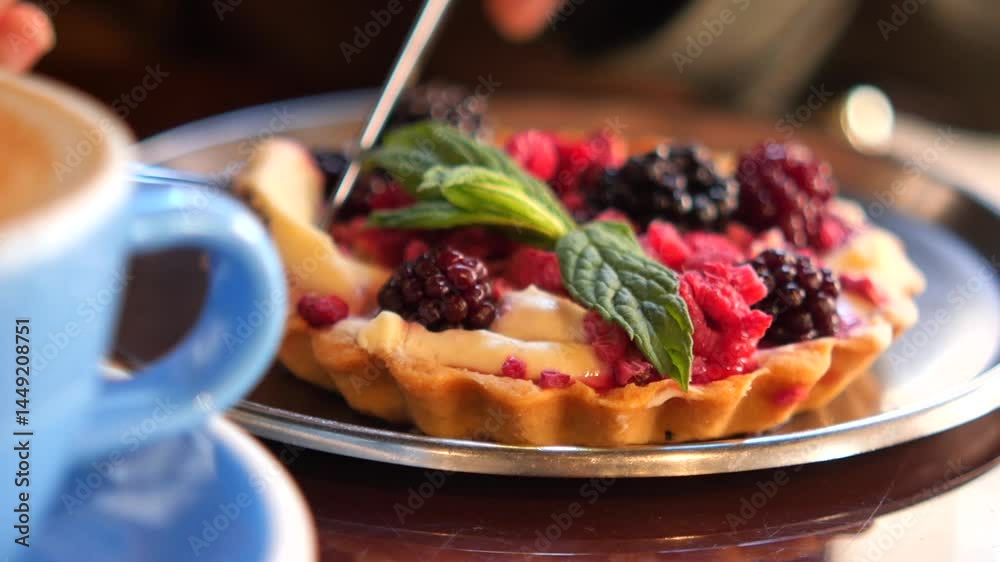 Indulging in berry tart with fresh mint in cozy cafe setting Indulging in berry tart with fresh mint in cozy cafe setting