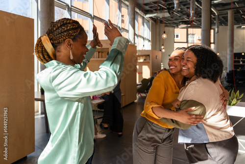Happy reunion of three women embracing in bright indoor space