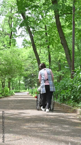 Wallpaper Mural 新緑の中車椅子を押して散歩しながら介護する介護士と高齢者の全身の縦動画顔無し Torontodigital.ca