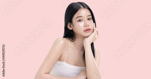 Glowing skin make up style of beautiful young Asian model isolated on pink background.