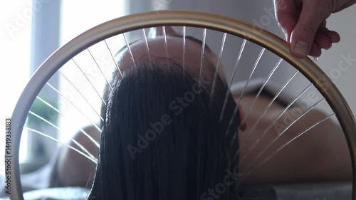 Close-up of a woman receiving a head massage during a Japanese head spa treatment with water flowing from a special hair washing tool, focusing on the scalp relaxation and beauty therapy