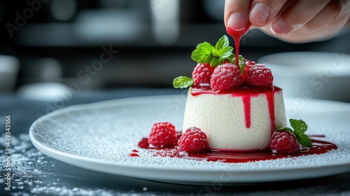 Delicate raspberry coulis drizzled over matcha panna cotta by skilled chef's hand