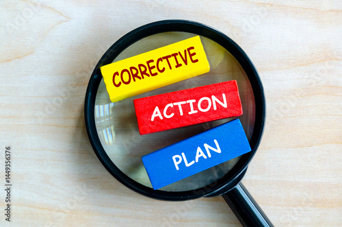 Corrective Action Plan text on colored wooden blocks with magnifying glass as background. Root cause analysis concept