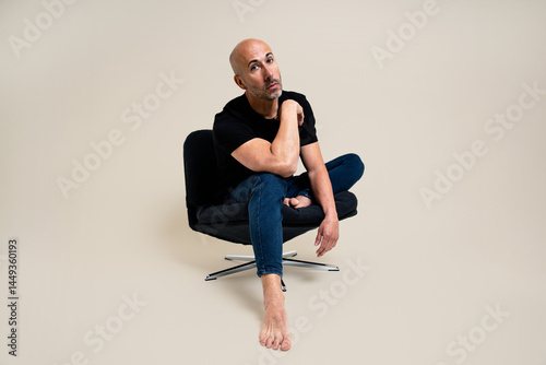  Man sitting cross-legged on a black swivel chair photo