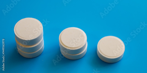 Canvas Print Three stacks of white round tablets of different heights are arranged on a bright blue background