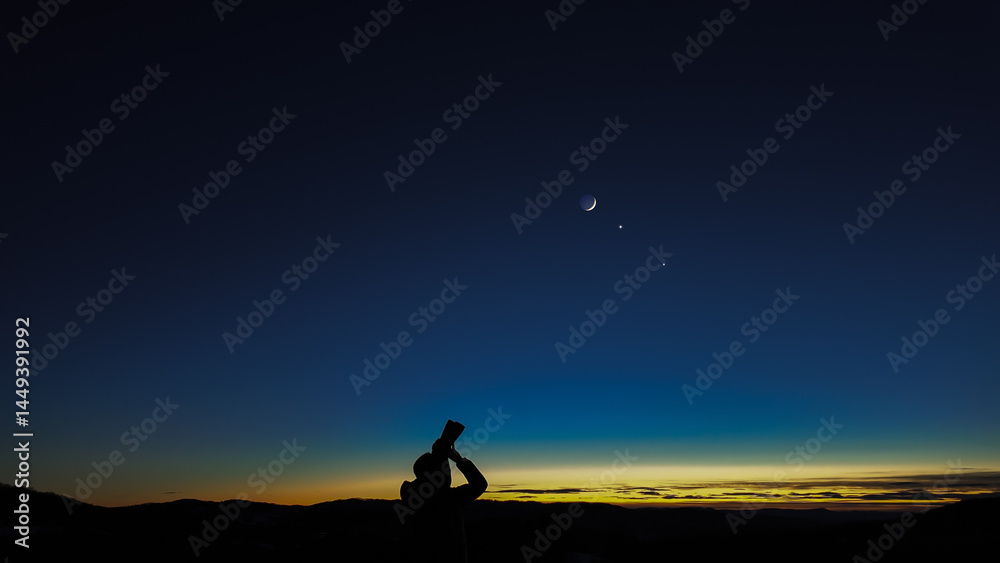 Amateur astronomer looking at the evening skies, observing planets, stars, Moon and other celestial objects with binoculars.