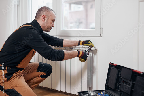 Obraz na płótnie Central heating mechanic and handyman fixing home radiator, gas crisis and seasonal issues. w salonie